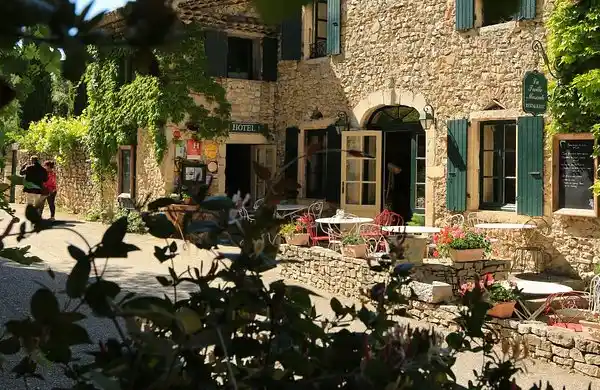 Façade en pierre et terrasse fleurie au cœur du village de Cliousclat