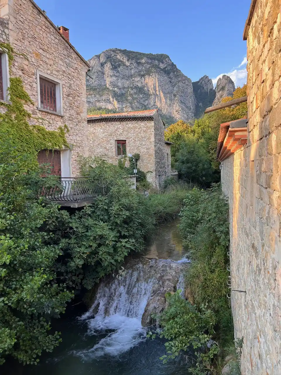 Maisons de pierre de Saoû au bord d’une cascade, falaises en arrière-plan