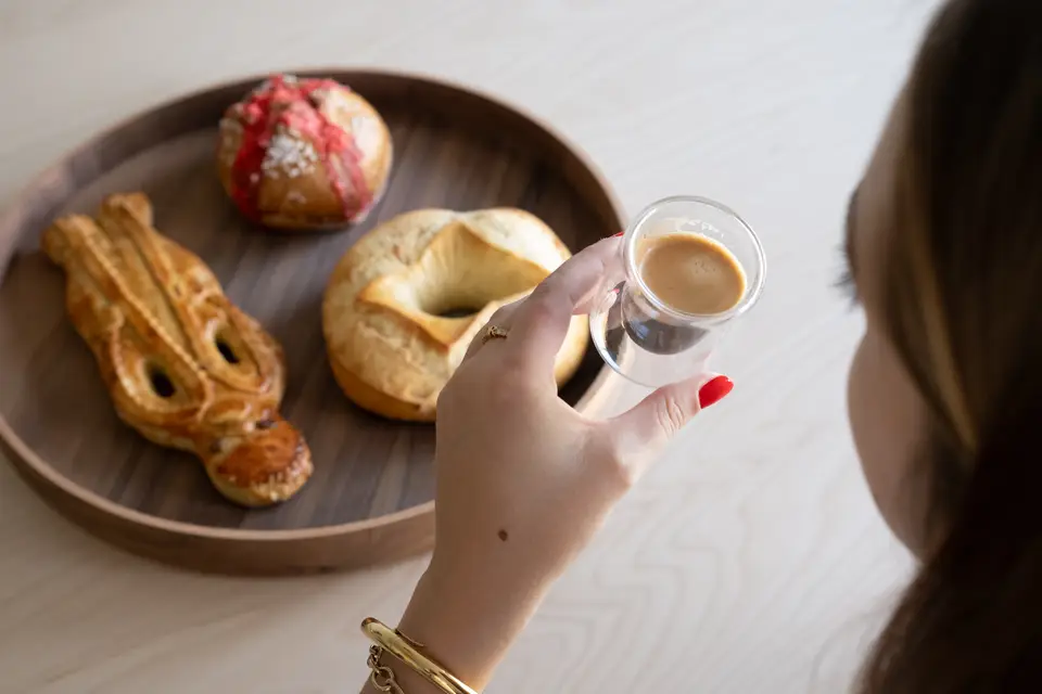 Suisse, pogne et brioche aux pralines sur un plateau en bois, un café à la main